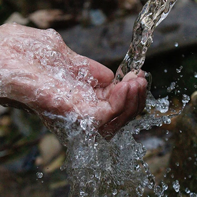 Crystal clear water pouring into person's hand